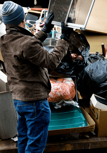 Man tossing residential junk and debris into large metal container