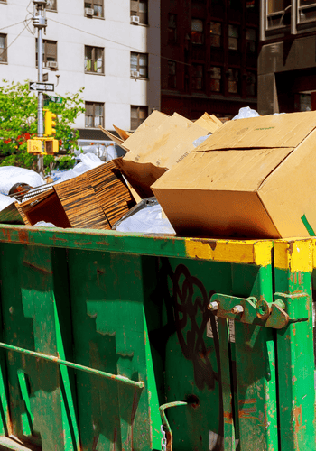 Green metal large bin with commercial junk inside of it