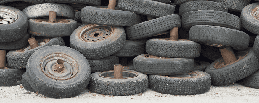 Dirty old tires strewn about on a gravel road