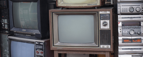 TVs stacked on top of each other in a large pile.