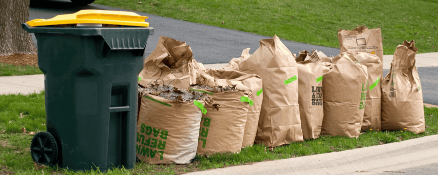 Brown bags full of yard debris sitting at corner of curb