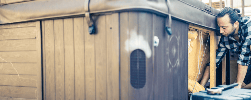 Man leaning down by hot tub preparing it for removal